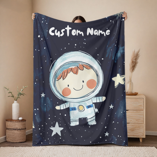 Personalized astronaut baby blanket with custom name, cute space explorer character design on navy starry background, nursery decor mockup