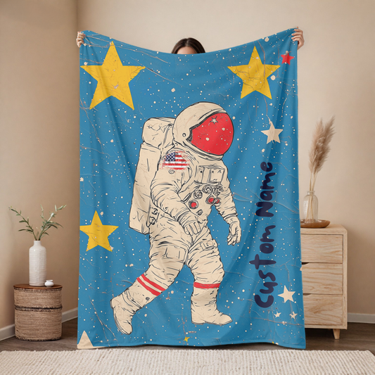 Personalized astronaut baby blanket with custom name, red visor space explorer design on blue background with stars, nursery decor mockup